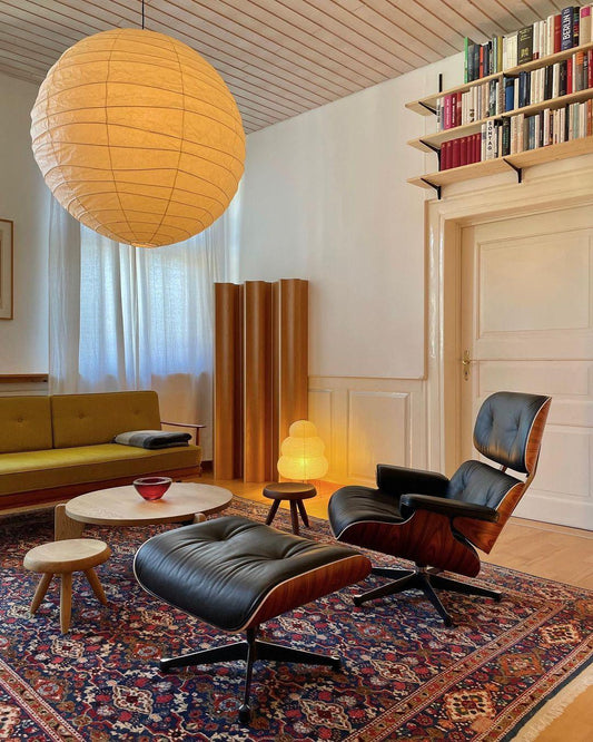 Large glowing paper pendant above a lounge with black leather chairs