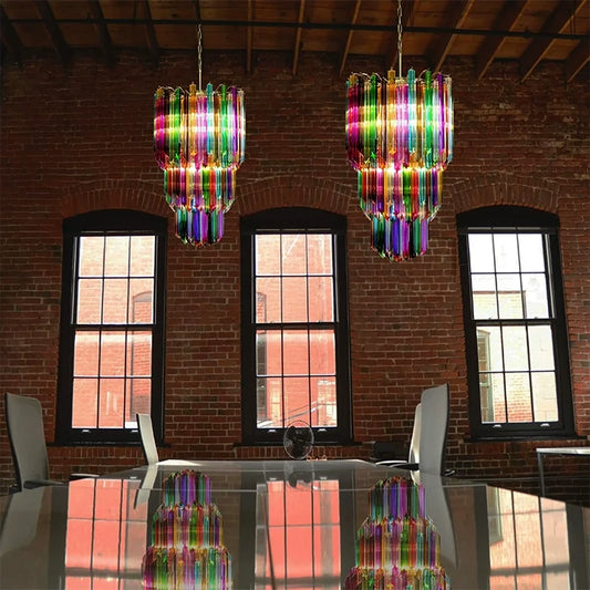 Pair of multicolor glass chandeliers above a reflective dining table in a brick loft