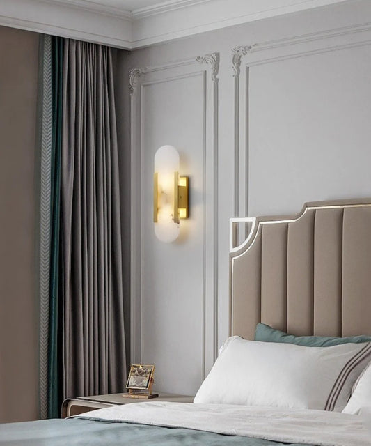 Contemporary Alabaster Wall Lamp beside an upholstered bed and dark curtains