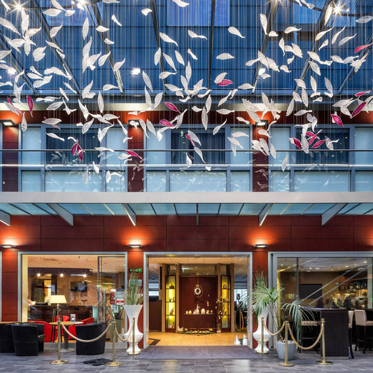Flying Glass Feather Chandelier seen above a large interior entrance from across an atrium