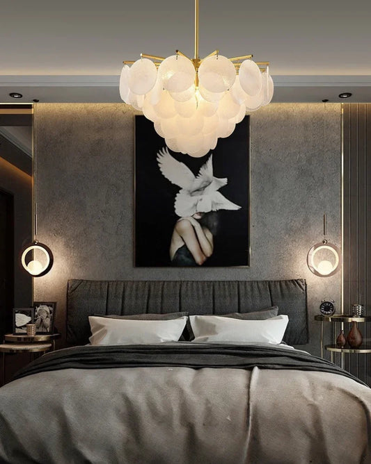 Frosted glass chandelier centered above a dark hotel-style bed