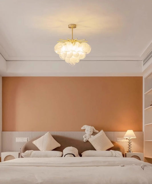 Warm hotel-style bedroom with a frosted glass chandelier