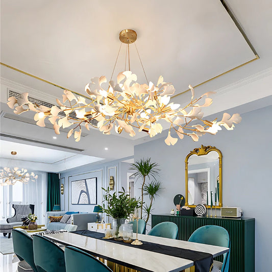 Wide ceramic ginkgo chandelier above a marble dining table with teal chairs