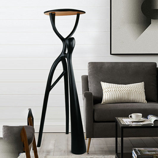 Human Standing Floor Lamp beside a dark lounge chair and table