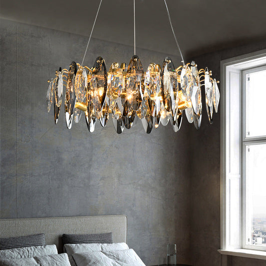 Smoke grey crystal chandelier suspended beside a window above a grey bed