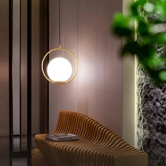 Single gold-framed globe pendant lighting a compact wood-paneled interior corner