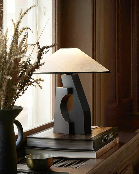 Ruins Wood Table Lamp on stacked books beside a window and dark vase