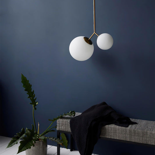 Two softly glowing white glass globes above a bench in a dark blue lounge