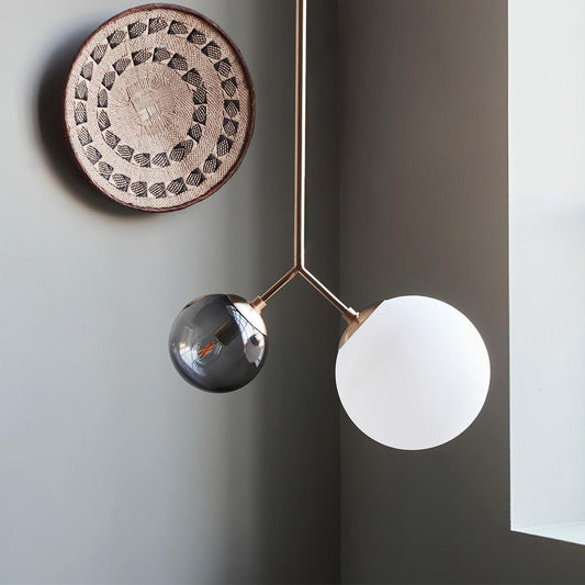 Pendant with one smoky transparent globe and one white frosted globe in a gray living room